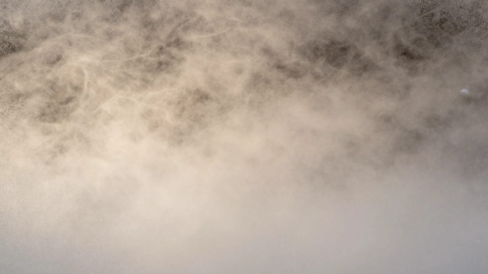 Fotografía abstracta de niebla fría sobre cristal esmerilado con contraluz cálido, metáfora de la remodelación por frío controlado.